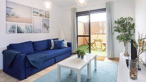 A modern living room with a blue sofa, white coffee table, and artwork on the wall. - Home2Book Sea Side El Medano (El Medano)