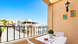 A balcony with a table and chairs, a potted plant, and a street view. - Home2Book Jable Beach Apartment (Morro Jable)