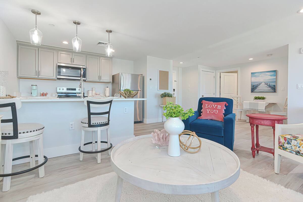 A modern kitchen with stainless steel appliances, a dining area with a round table, and a blue chair with a cushion.