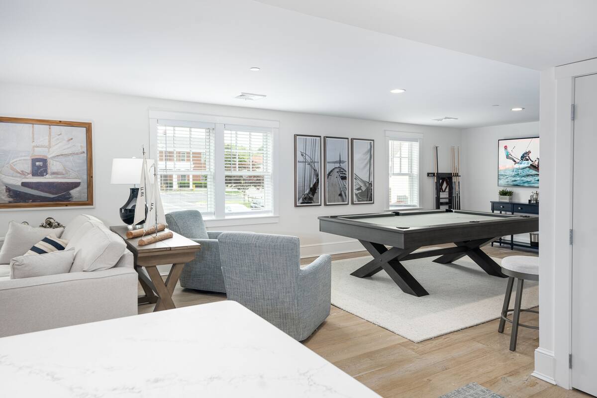 A modern living room with a pool table, a sofa, and a dining table.