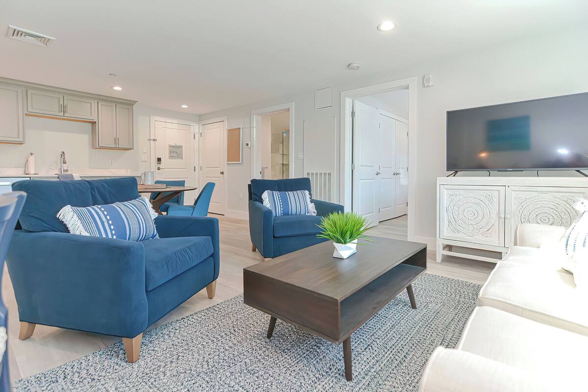 A modern living room with blue sofas, a coffee table, and a TV.