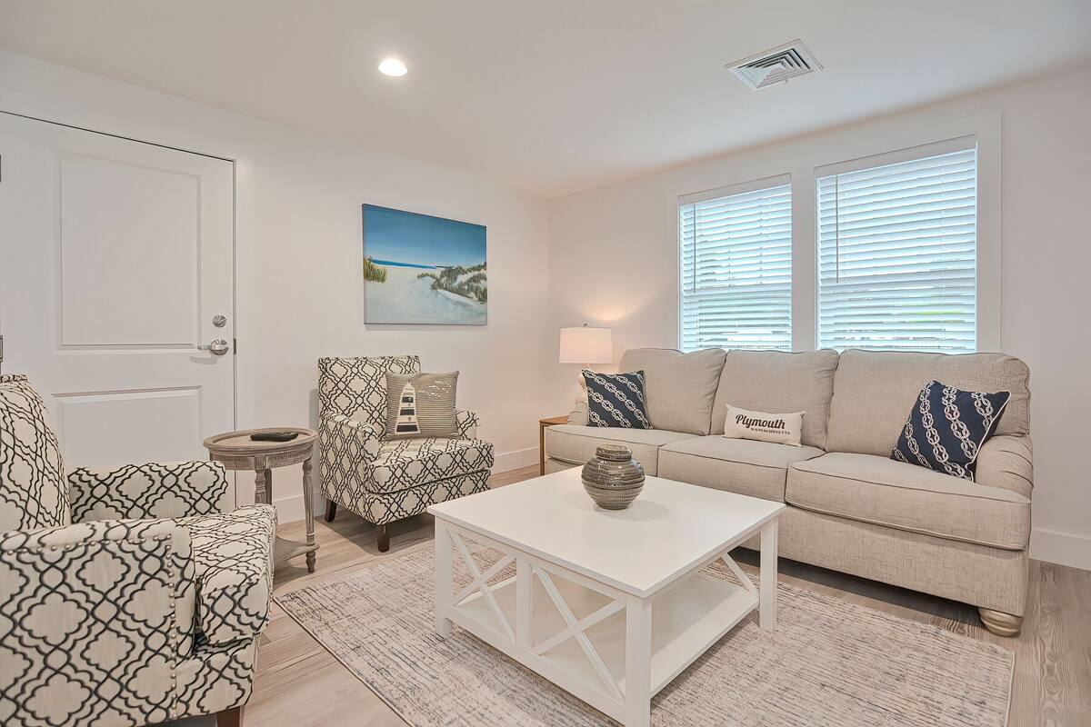 A living room with a beige sofa, patterned armchairs, a white coffee table, and a painting of a snowy landscape.