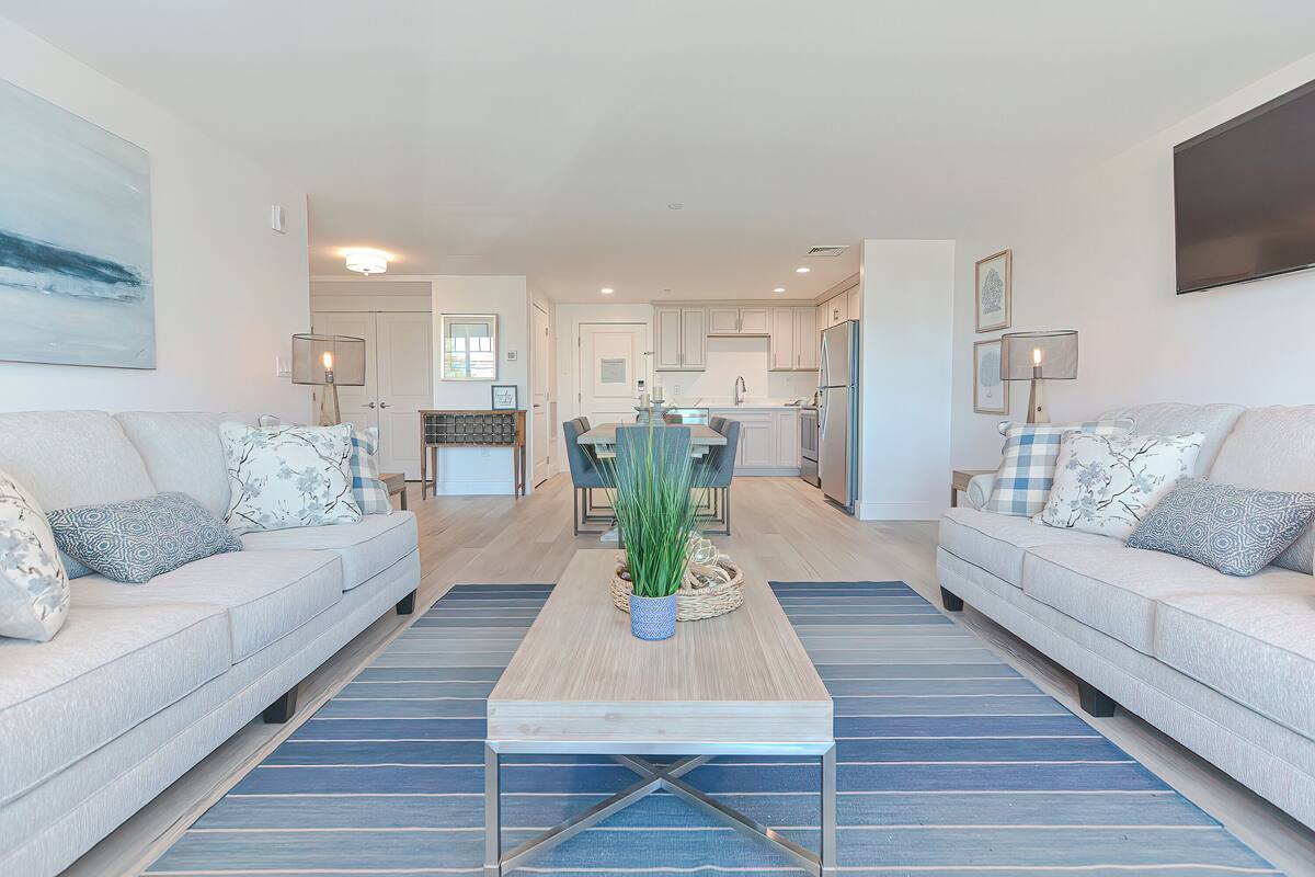 A modern living room with a sofa, coffee table, and a view into the kitchen.