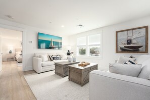 A modern living room with a white sofa, two wooden coffee tables, and a large painting of a sailboat. - Thomas Sea Suites (Plymouth)