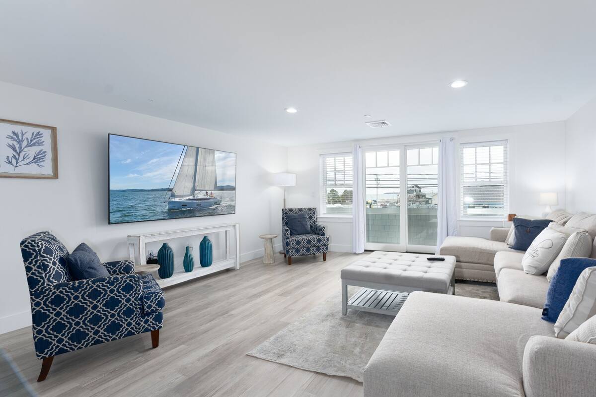 A modern living room with a large window, a fireplace, and a view of the sea.