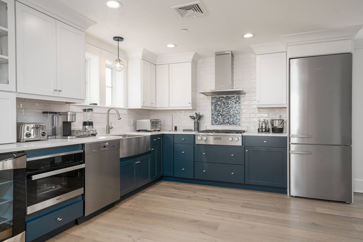 A modern kitchen with white cabinets, a stainless steel refrigerator, and a built-in oven.