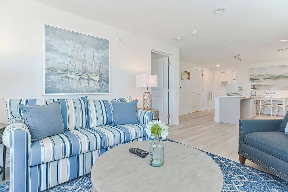 A modern living room with a striped sofa, a coffee table with a vase, and a painting on the wall.