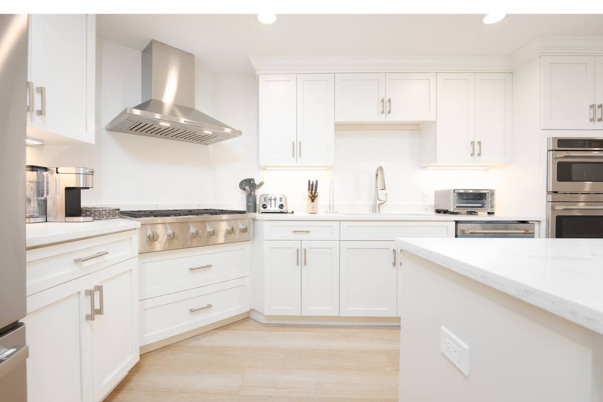 A modern kitchen with white cabinetry, stainless steel appliances, and a central island.