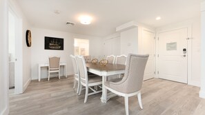 A dining area with a white table and chairs, a wall clock, and a framed picture. - Thomas Sea Suites (Plymouth)
