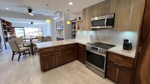 A modern kitchen with wooden cabinets, a stainless steel stove, and a marble countertop. - Beach Front Pool Fully Kitchen Breathtaking Sea Views Close to Everything (San Jose Del Cabo)