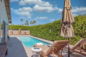 A poolside area with lounge chairs, a table, and an umbrella. - Casa Mesquite - Lovely Bungalow in S Palm Springs (Palm Springs)