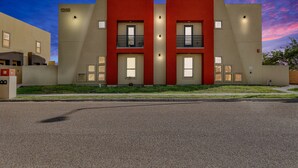 A modern building with two red sections and beige walls, featuring balconies and large windows. - Relax & Enjoy In Our Spacious Townhome Getaway! (McAllen)