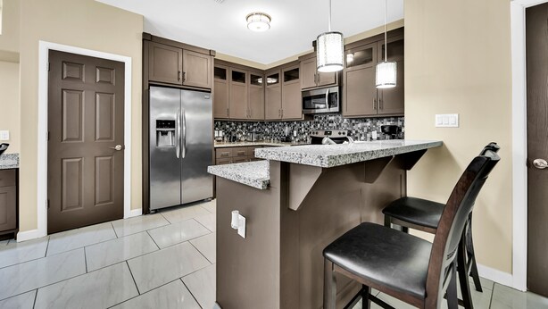 A modern kitchen with a central island, stainless steel appliances, and pendant lighting. - Relax & Enjoy In Our Spacious Townhome Getaway! (McAllen)