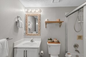 Une salle de bain avec un lavabo blanc, un meuble-lavabo, des toilettes et un espace douche.