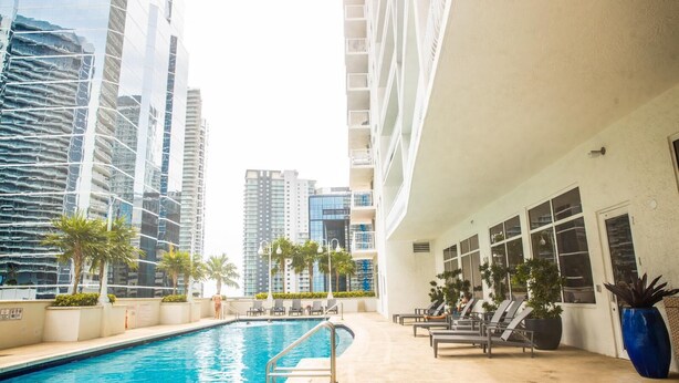 A swimming pool with lounge chairs and palm trees, surrounded by high-rise buildings. - **NEW** Ocean Front 3 Bedroom Apartment in the heart of Brickell (Miami)