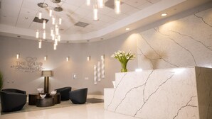 A modern reception area with a marble reception desk, black seating, pendant lighting, and a wall-mounted sign. - **NEW** Ocean Front 3 Bedroom Apartment in the heart of Brickell (Miami)