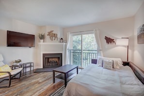 Relax in a serene space with a comfortable bed, modern sofa, and fireplace.