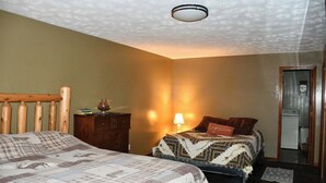 Un dormitorio con dos camas, cabecero de madera, mesita de noche, lámpara y espejo.