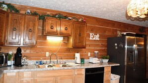 Una cocina con armarios de madera, un refrigerador de acero inoxidable, un lavamanos y una encimera con varios electrodomésticos y adornos.