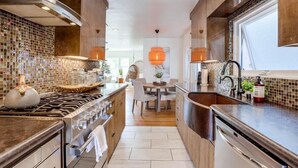 Una cocina moderna con una isla central, electrodomésticos de acero inoxidable y vistas al área de comedor.