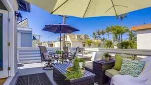 Una terraza en la azotea con mobiliario exterior, una pérgola y vistas a casas vecinas.