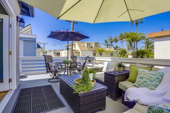A rooftop patio with outdoor furniture, a pergola, and a view of neighboring houses.