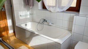 Bathtub, hair dryer, towels, toilet paper