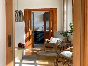 A cozy room with a wooden door leading to a kitchen, a wicker chair, a small table, and a potted plant. - Vacation apartment Ava- Heiligkreuztal for 2-6 persons (Altheim- Heiligkreuztal)