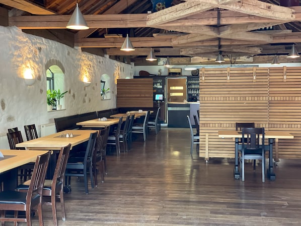 A restaurant with wooden tables and chairs, a counter, and a stone wall with arched windows. - Vacation apartment Ava- Heiligkreuztal for 2-6 persons (Altheim- Heiligkreuztal)
