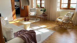 A cozy living room with a sofa, a rocking chair, a coffee table, and a dining area with a table and chairs.