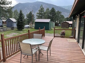 A deck with a table and chairs, overlooking a mountainous area with several cabins. - Pine Street Getaway - Quiet Location Close to Town (Permit #Tlcr36) (Lake City)