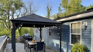 Un patio extérieur abrité, équipé d’un barbecue, d’une table à manger et de chaises.