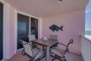 Un balcon avec une table et des chaises, une décoration murale représentant des poissons, et une vue sur l’océan.