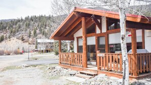 A wooden cabin with a porch, large windows, and a view of a mountainous landscape. - 3 bedroom accommodation in Red River (Red River)