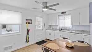 A modern kitchen with white cabinets, a granite countertop, and a ceiling fan.