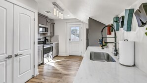 Una cocina moderna con armarios blancos, electrodomésticos de acero inoxidable y suelo de madera.