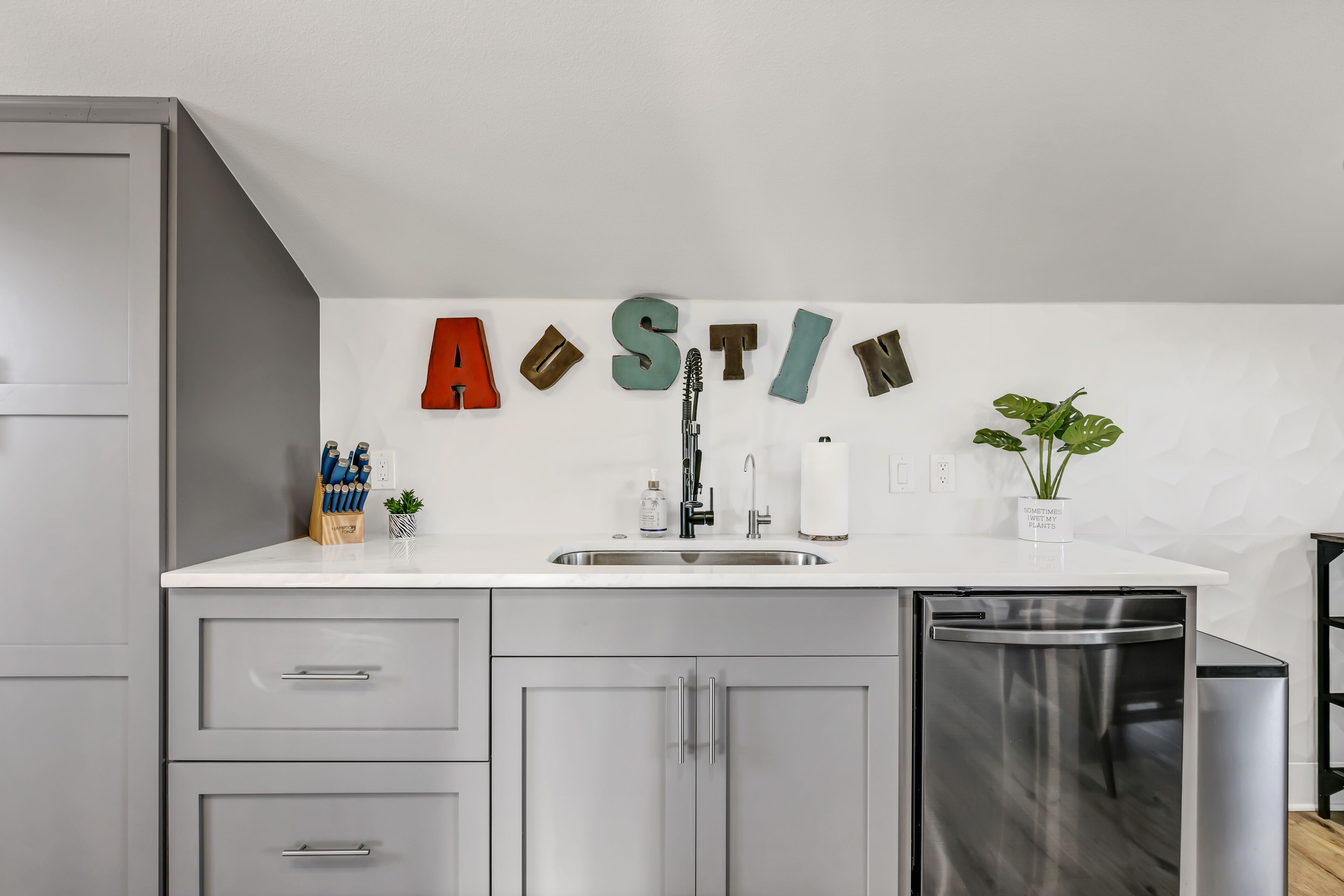 A modern kitchen with a sink, cabinets, and a dishwasher.