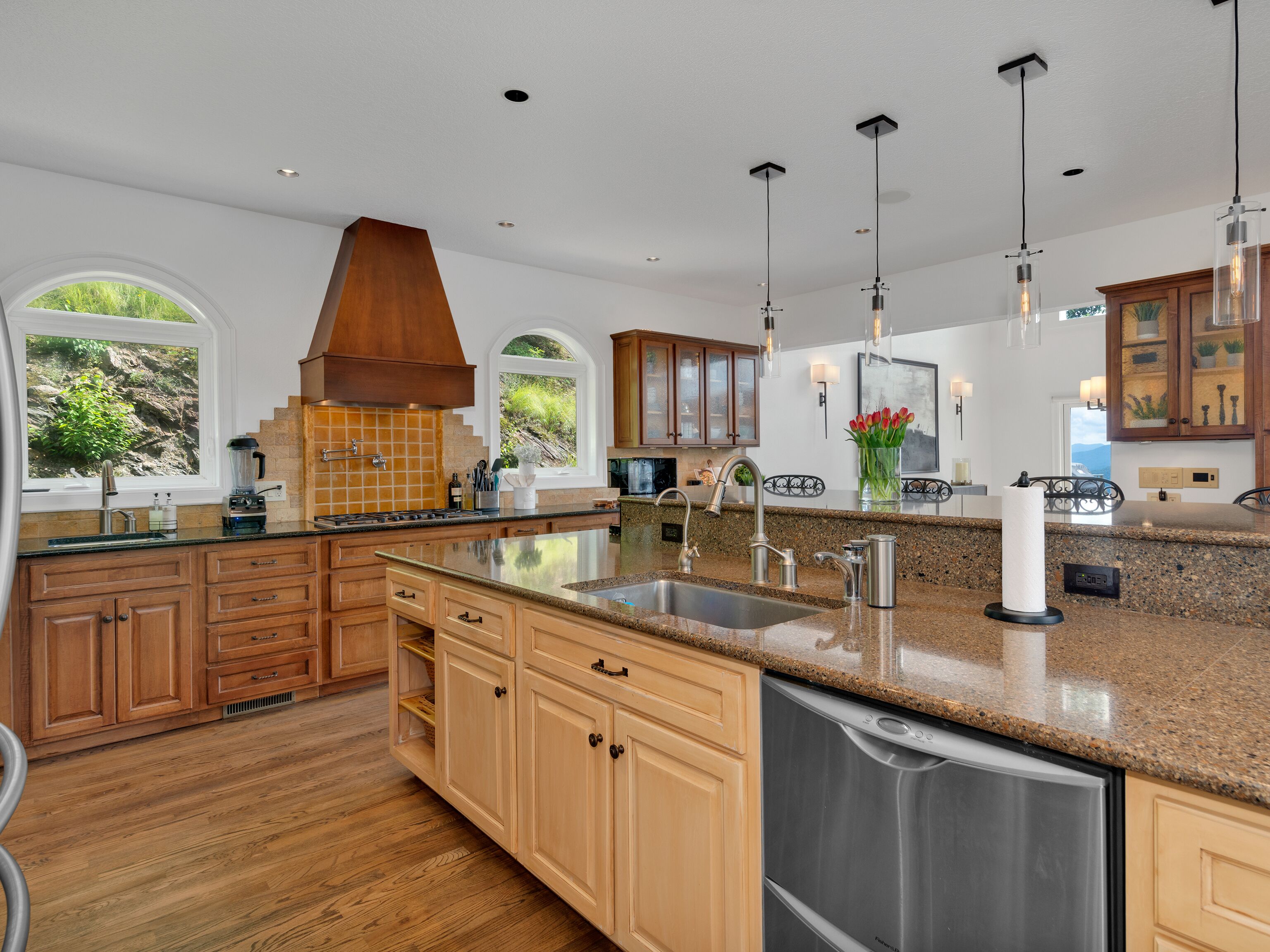 A spacious kitchen with a large island, wooden cabinetry, and a view through the windows.