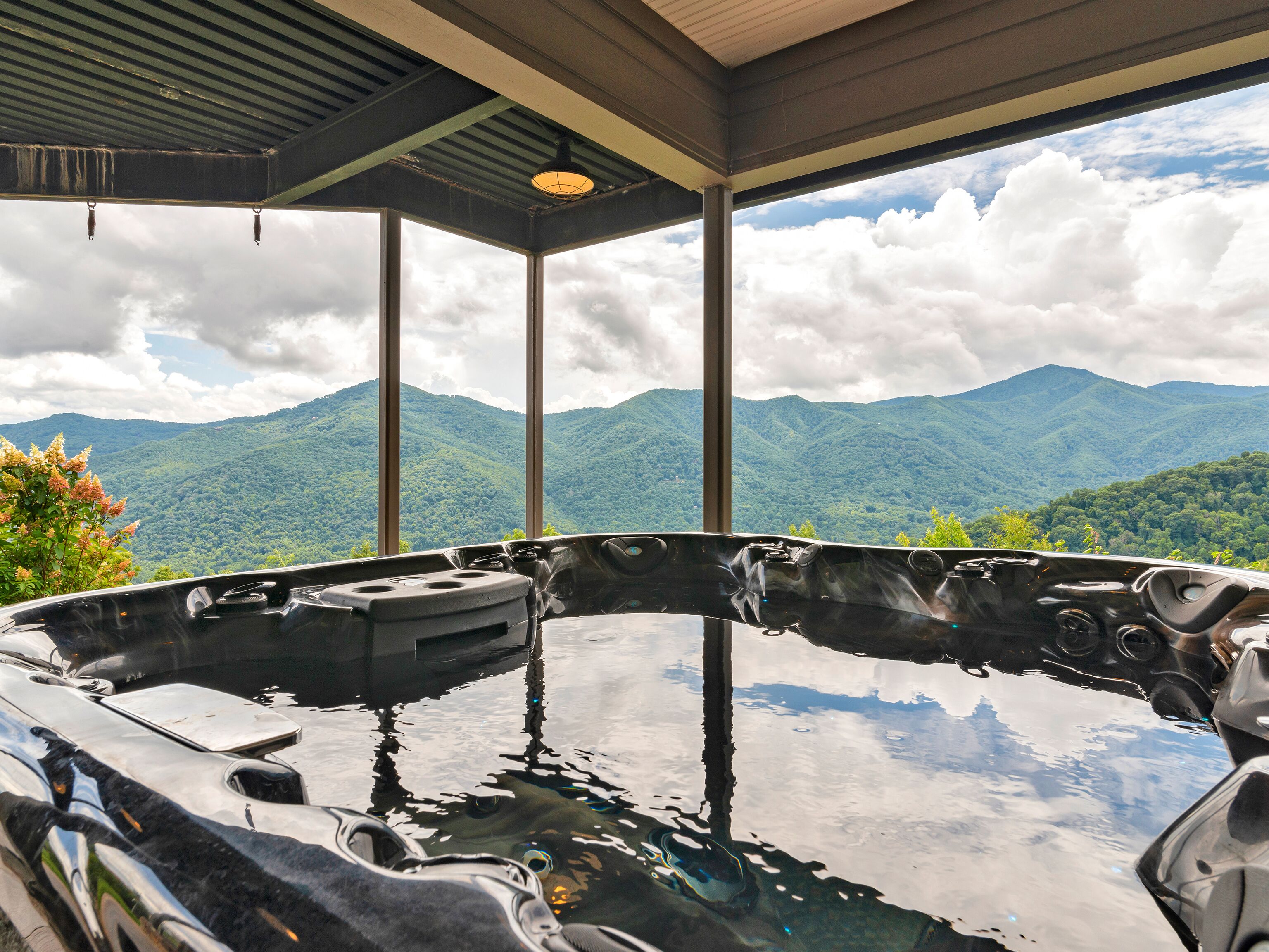 A hot tub with a mountain view, large windows, and a covered roof.