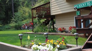 A residential house with a front garden, a wooden deck, and a visible street sign. - Woodsy Escape Located south of Kalispell Montana (Kalispell)