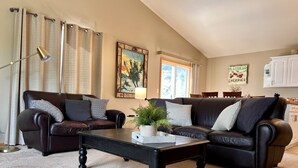 A living room with two leather sofas, a black coffee table, a floor lamp, and a painting on the wall. - Woodsy Escape Located south of Kalispell Montana (Kalispell)
