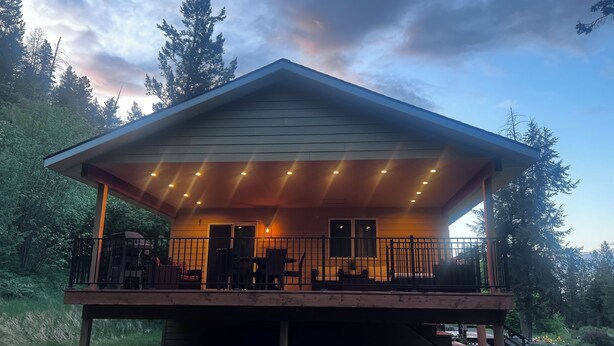 A covered outdoor deck with a railing, a door, and a window. - Woodsy Escape Located south of Kalispell Montana (Kalispell)