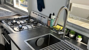 A kitchen with a gas stove, sink, and window.
