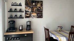 Een keuken met een koffiehoek, een koffiezetapparaat en een wand met kunstwerken over koffie.