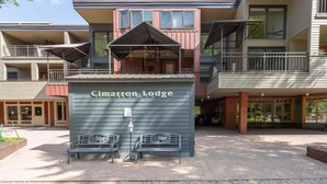 A building with a sign reading "Cimarron Lodge" and a covered outdoor seating area with benches. - Serenity at Cimarron Lodge! Hot Tub, Parking (Telluride)