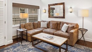A living room with a sectional sofa, a coffee table, a side table, a lamp, and a large mirror on the wall. - Serenity at Cimarron Lodge! Hot Tub, Parking (Telluride)