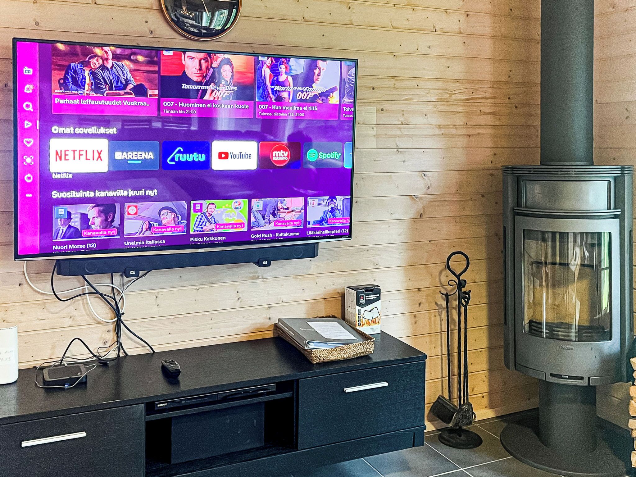 A flat-screen TV mounted on a wooden wall displaying various streaming services.