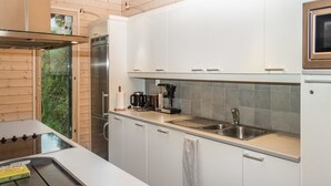 Una cucina moderna con mobili bianchi, un lavello in acciaio inossidabile e un forno integrato.