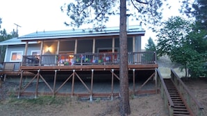 A two-story house with a balcony, a staircase leading to the upper level, and a metal railing. - Charming Waterfront Pine Cabin on Curlew Lake (Republic)