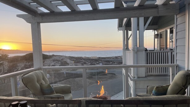 En hyggelig balkon med udsigt til stranden, en ildsted og en velkomstskilt.